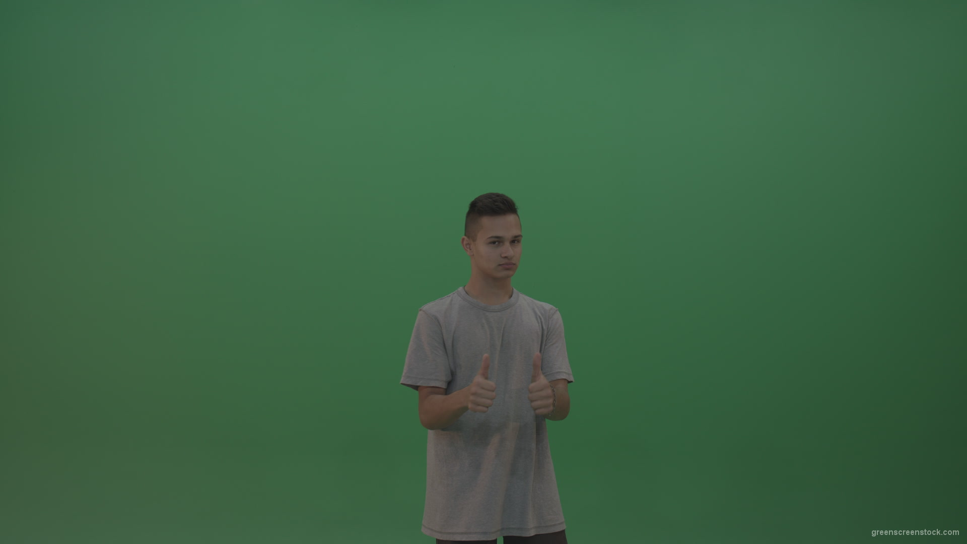 Boy-in-grey-wear-expresses-approval-by-giving-thumbs-up-over-green-screen-background_007 Green Screen Stock