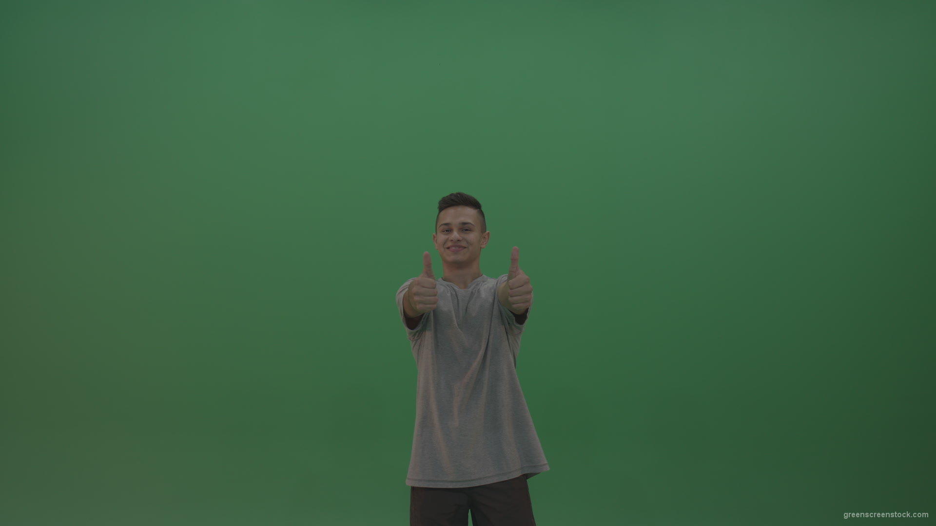Boy-in-grey-wear-expresses-approval-by-giving-thumbs-up-over-green-screen-background_009 Green Screen Stock