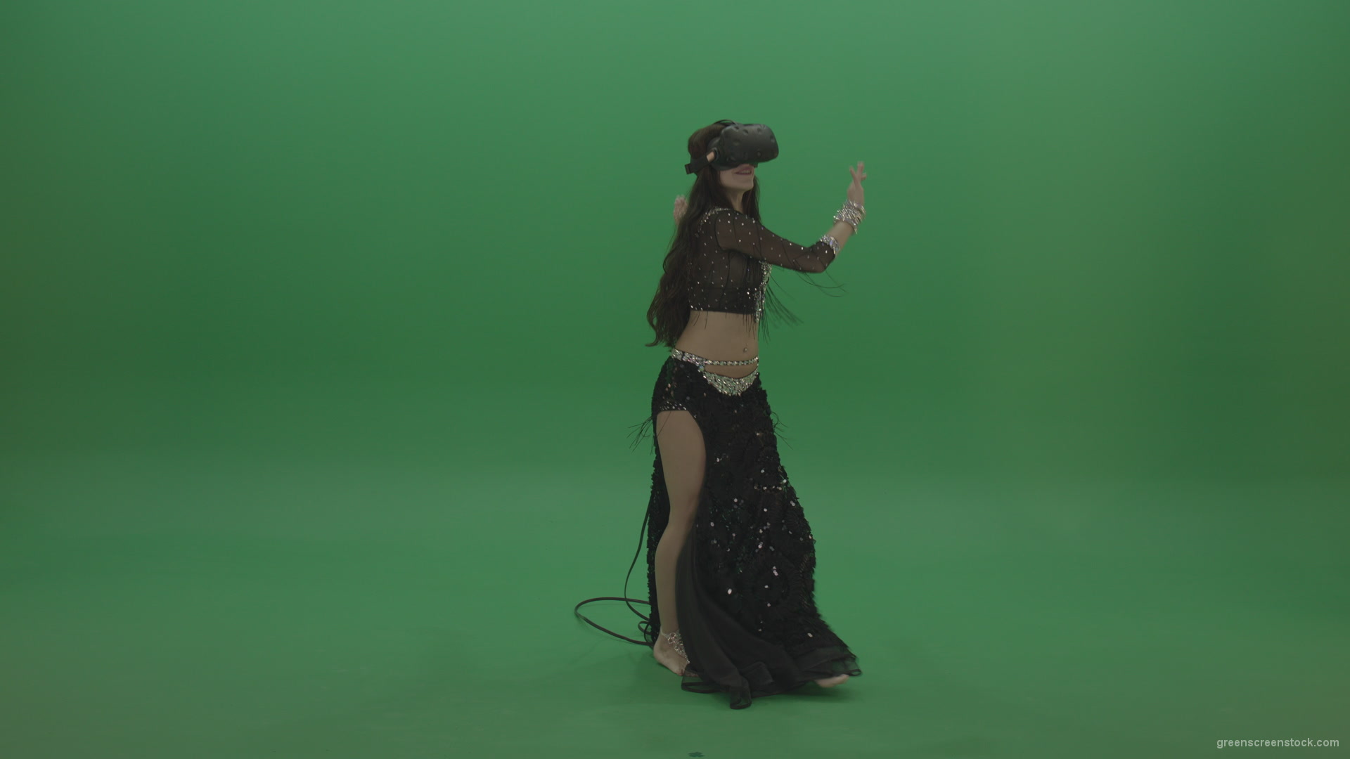 Beautiful belly dancer  in black wear and VR gear dances 
